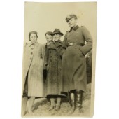 German officer in overcoat and visor hat with family